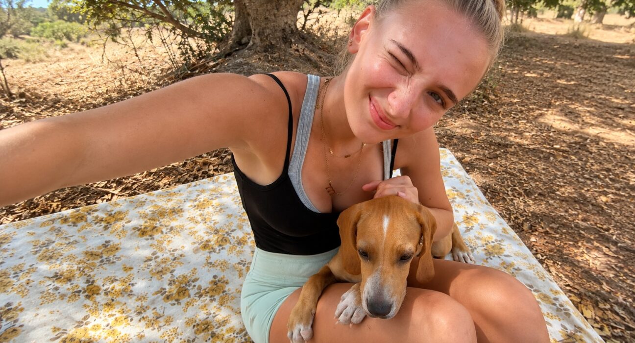 German student Luise sitting outdoors with Chilli Boy, a Maltese shelter dog adopted after her internship at the Association for Abandoned Animals.