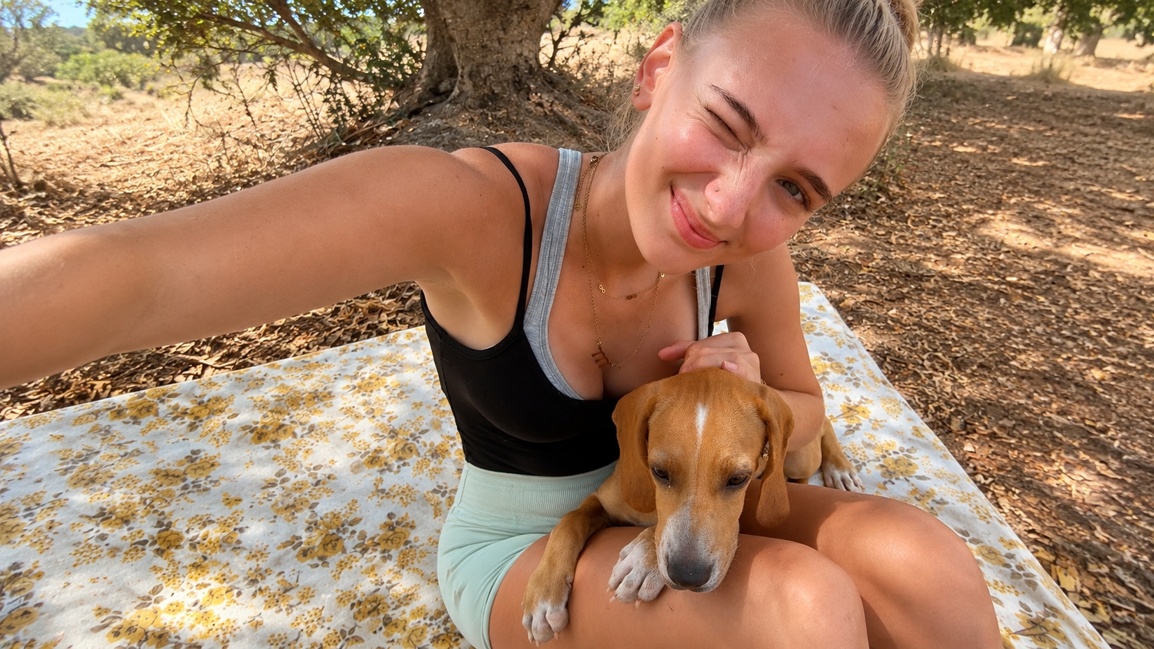 German student Luise sitting outdoors with Chilli Boy, a Maltese shelter dog adopted after her internship at the Association for Abandoned Animals.